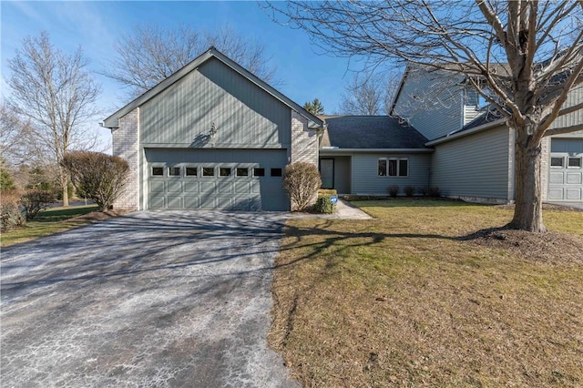 view of front of property featuring brick siding, driveway, a front lawn, and a garage