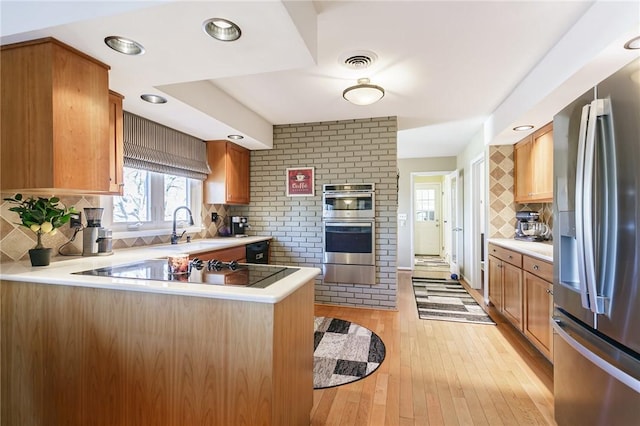 kitchen with visible vents, a peninsula, light countertops, light wood-style floors, and appliances with stainless steel finishes