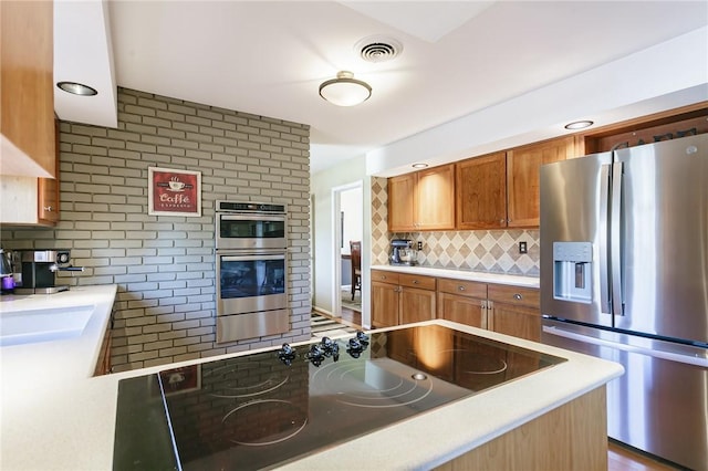 kitchen with visible vents, tasteful backsplash, stainless steel appliances, brown cabinetry, and a fireplace