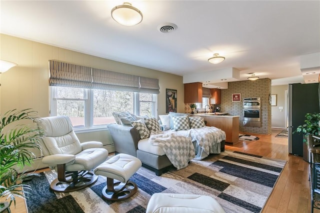 living area with hardwood / wood-style flooring, a fireplace, visible vents, and a baseboard radiator