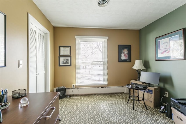 office area featuring a baseboard heating unit, plenty of natural light, and visible vents