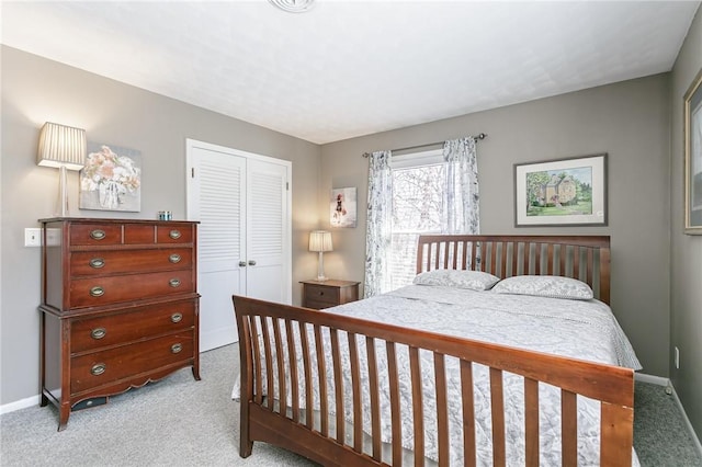 bedroom with a closet, light carpet, and baseboards