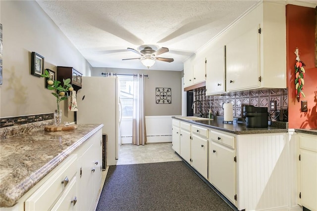 kitchen with ceiling fan, decorative backsplash, freestanding refrigerator, a textured ceiling, and a sink