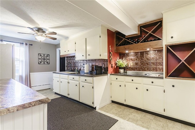 kitchen featuring a sink, ceiling fan, wainscoting, black electric stovetop, and baseboard heating