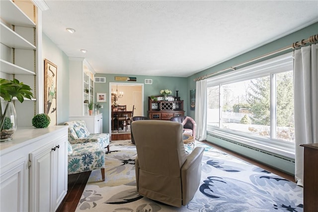 living area featuring visible vents, wood finished floors, and a baseboard radiator