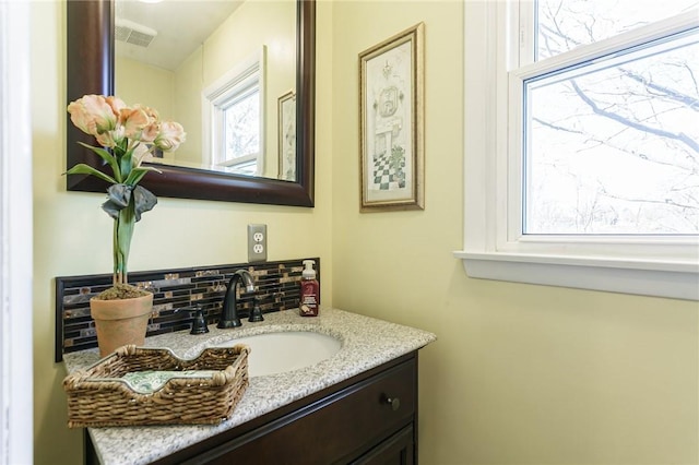 bathroom with decorative backsplash, vanity, and visible vents