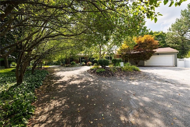 view of front of property with driveway, a garage, and fence