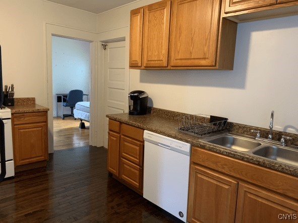 kitchen with brown cabinetry, dark wood finished floors, a sink, dishwasher, and dark countertops