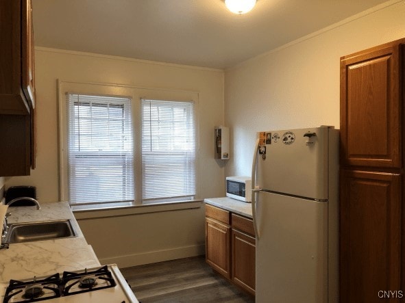 kitchen featuring a sink, dark wood-style floors, white appliances, crown molding, and light countertops