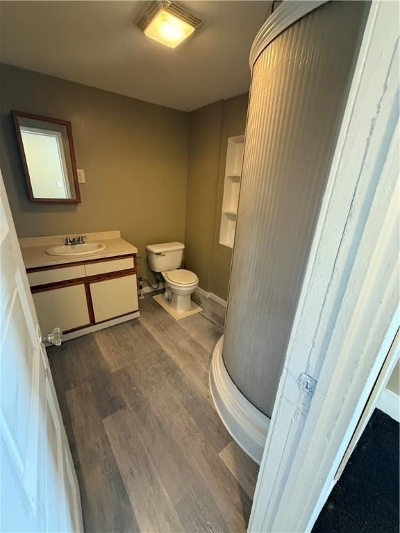 bathroom with toilet, vanity, and wood finished floors