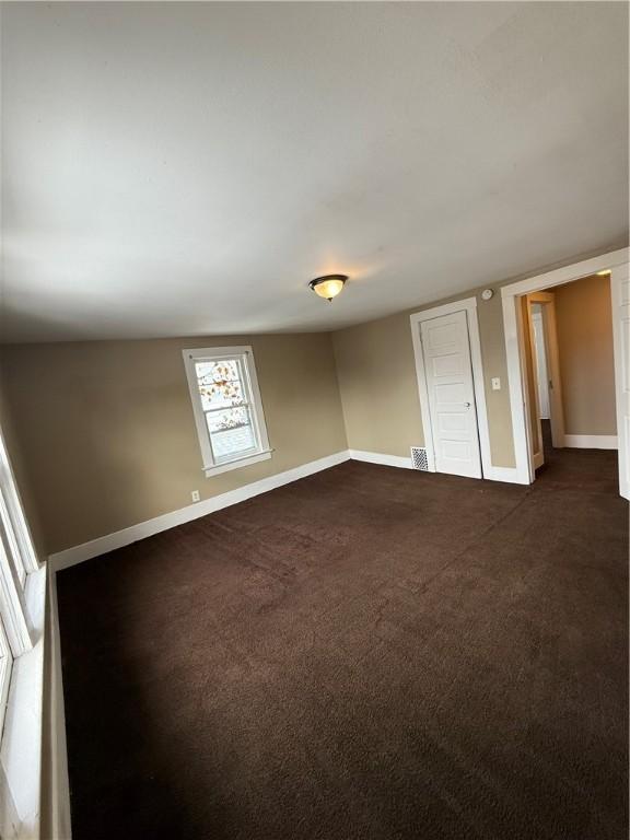 empty room featuring dark colored carpet, visible vents, and baseboards