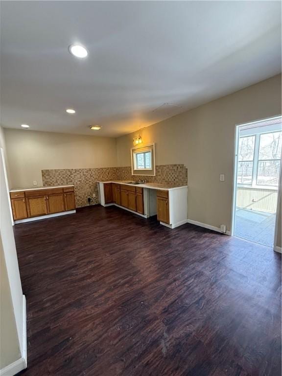 kitchen featuring baseboards, brown cabinets, dark wood-type flooring, and light countertops