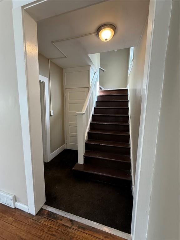 stairway with visible vents, baseboards, and wood finished floors