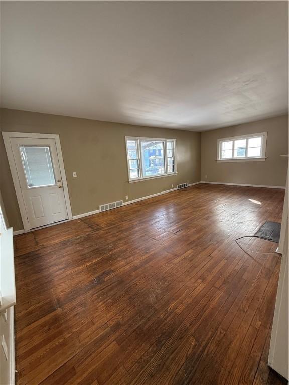 unfurnished room featuring baseboards, visible vents, and dark wood-style flooring