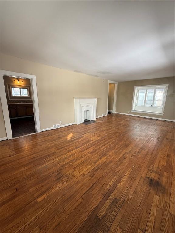 unfurnished living room with hardwood / wood-style flooring, plenty of natural light, a fireplace, and visible vents