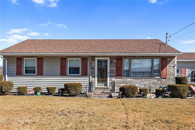 ranch-style home with stone siding, a front yard, and a shingled roof