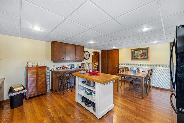 kitchen with open shelves, light wood finished floors, butcher block countertops, and freestanding refrigerator