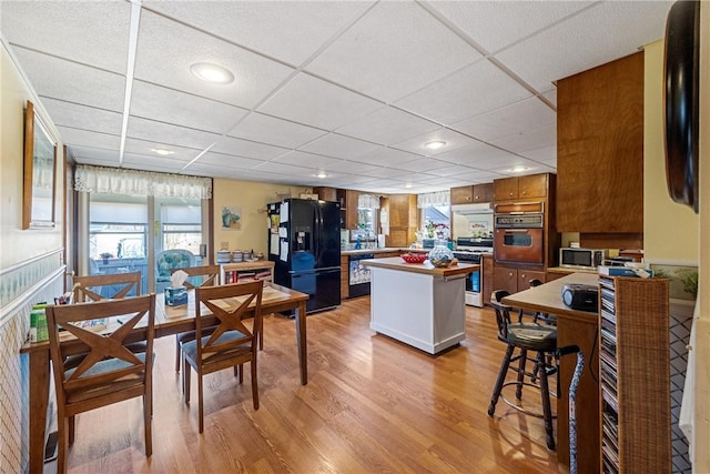 dining area with recessed lighting, a paneled ceiling, and light wood-style flooring