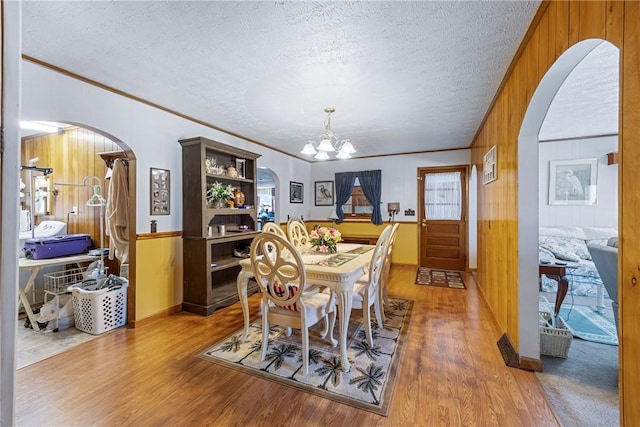 dining room featuring a notable chandelier, wood finished floors, arched walkways, and a textured ceiling