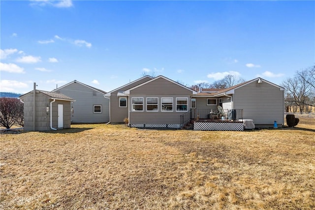 rear view of property with a lawn, a wooden deck, a storage shed, and an outdoor structure