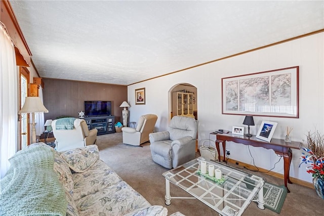 living area featuring arched walkways, carpet flooring, and crown molding