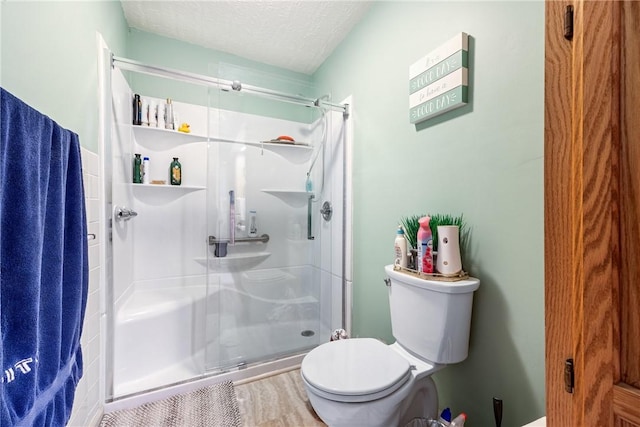 full bath featuring a shower stall, toilet, and a textured ceiling