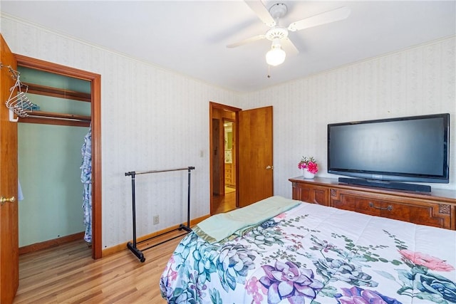 bedroom with wallpapered walls, wood finished floors, baseboards, and a closet