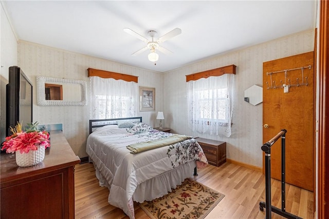 bedroom with wallpapered walls, wood finished floors, baseboards, and a ceiling fan