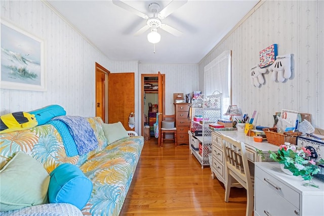 interior space featuring wallpapered walls, a ceiling fan, light wood finished floors, and ornamental molding