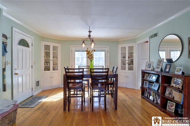 dining space featuring visible vents, ornamental molding, and light wood finished floors