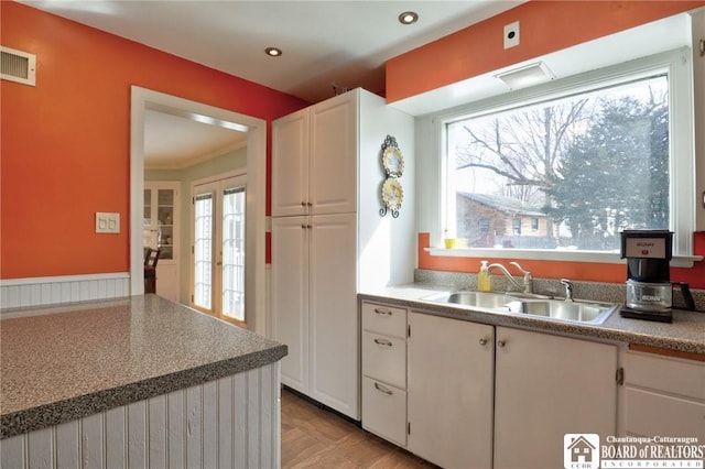 kitchen with visible vents, a sink, recessed lighting, french doors, and white cabinets