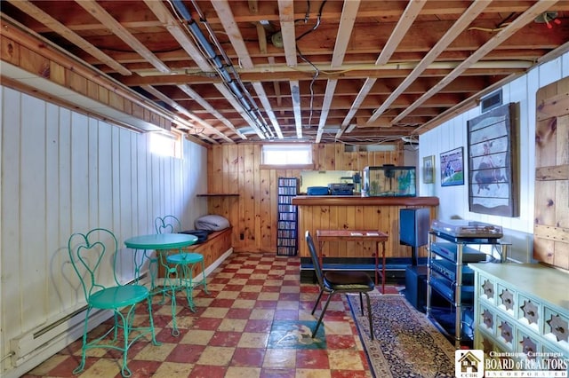 basement featuring a baseboard heating unit, tile patterned floors, and wood walls