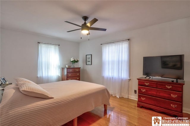 bedroom with light wood finished floors, multiple windows, and a ceiling fan