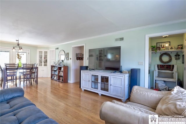 living area featuring light wood finished floors, visible vents, and crown molding