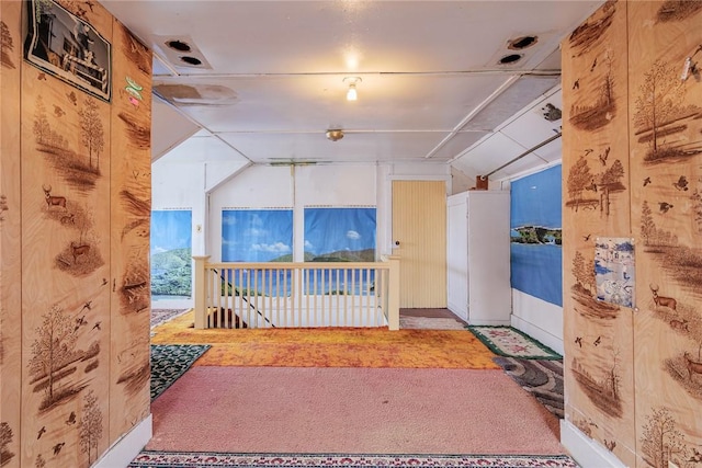 hallway with lofted ceiling, an upstairs landing, and carpet flooring