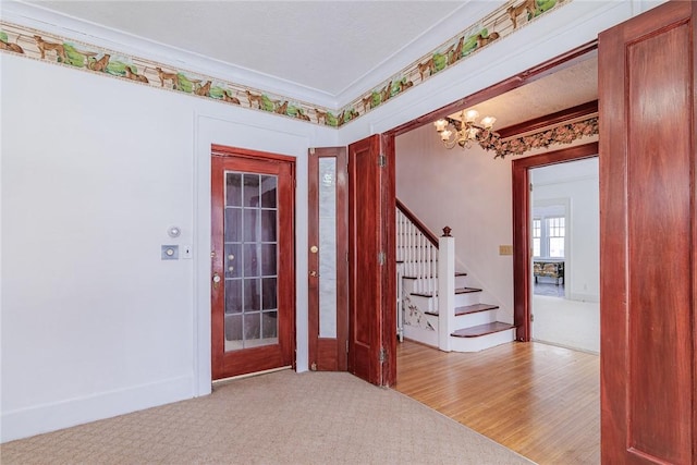 foyer featuring light colored carpet, ornamental molding, and stairs