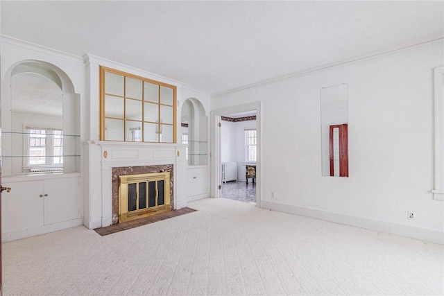 unfurnished living room featuring arched walkways, a healthy amount of sunlight, crown molding, and a premium fireplace