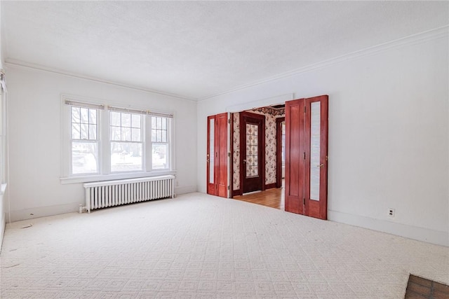 carpeted empty room featuring baseboards, ornamental molding, and radiator heating unit