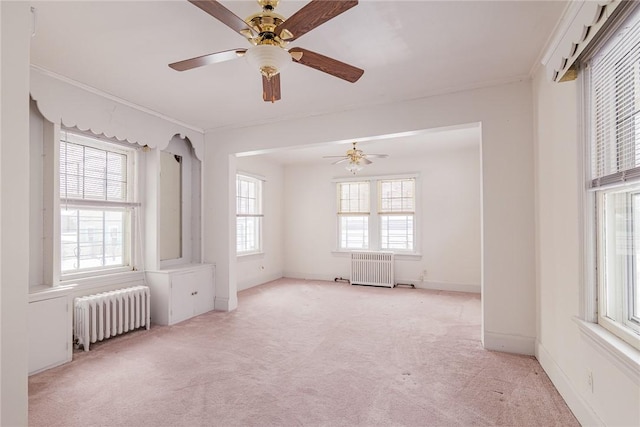 spare room featuring ornamental molding, radiator heating unit, baseboards, and light carpet