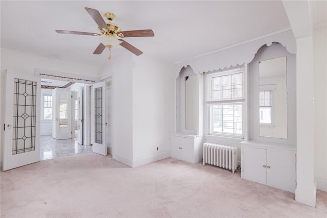 empty room featuring light carpet, plenty of natural light, crown molding, and radiator heating unit