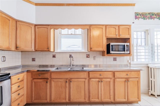 kitchen featuring stainless steel microwave, ornamental molding, stainless steel counters, decorative backsplash, and a sink