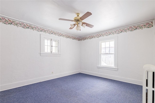 carpeted empty room featuring a healthy amount of sunlight, baseboards, crown molding, and a ceiling fan