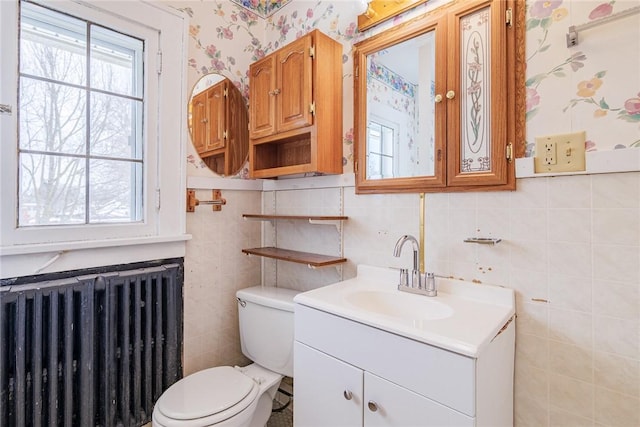 bathroom featuring radiator, wallpapered walls, toilet, vanity, and tile walls