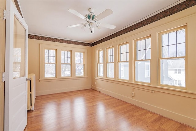 unfurnished sunroom featuring radiator heating unit and a ceiling fan