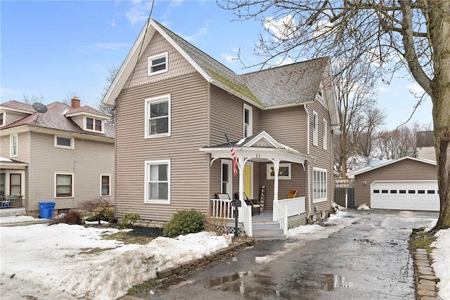 victorian house featuring an outbuilding, covered porch, a shingled roof, and a garage