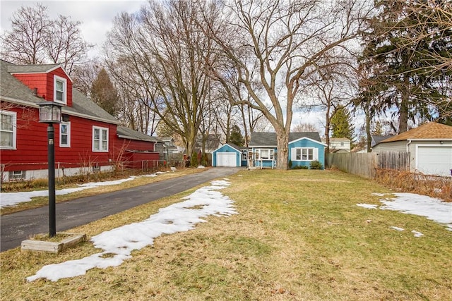 view of yard featuring a detached garage, an outdoor structure, driveway, and fence