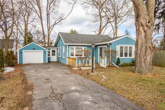 view of front of house with a garage, roof with shingles, driveway, and fence