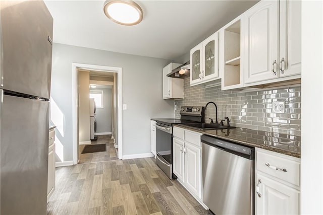 kitchen featuring a sink, stainless steel appliances, light wood-style floors, white cabinetry, and tasteful backsplash