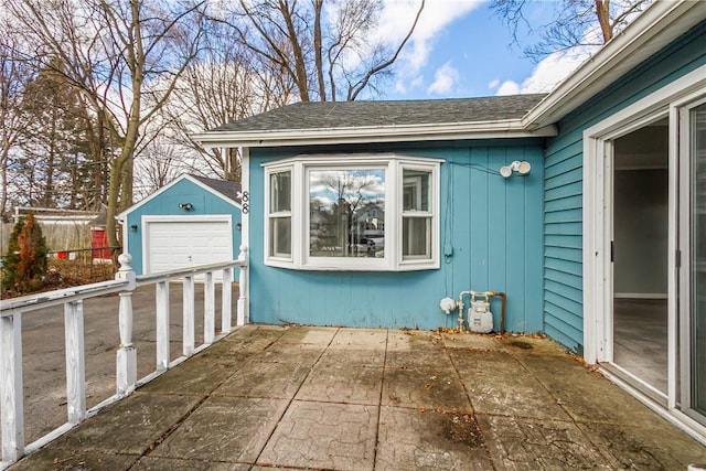 view of patio / terrace featuring a garage, an outbuilding, and fence