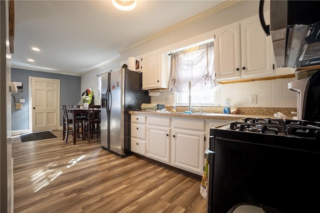 kitchen featuring wood finished floors, stainless steel fridge, ornamental molding, and white cabinetry